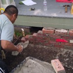 Raul lays a course of bricks.
